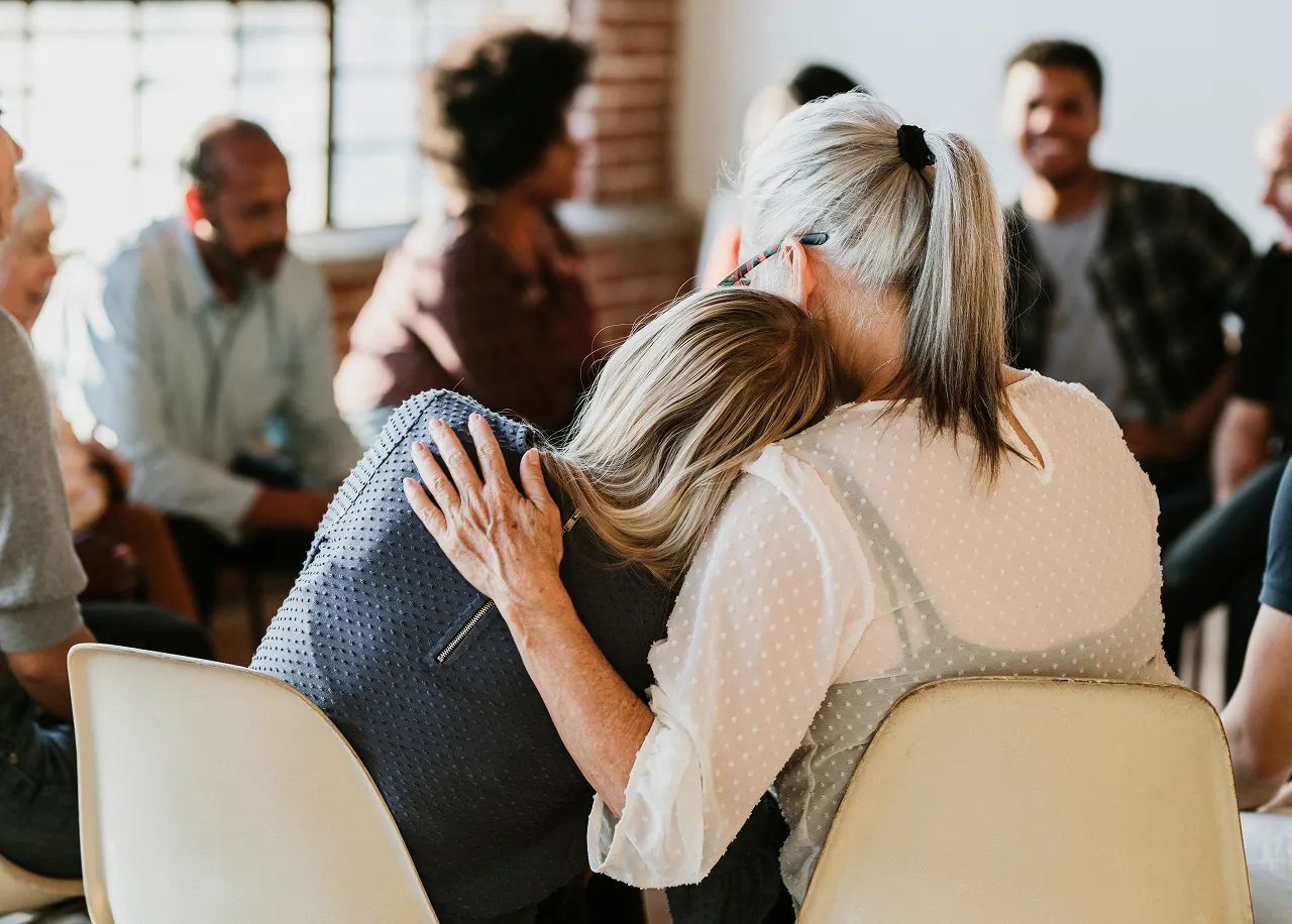 Two women embracing during emotional moment at grief counseling session in Virginia Beach therapy office